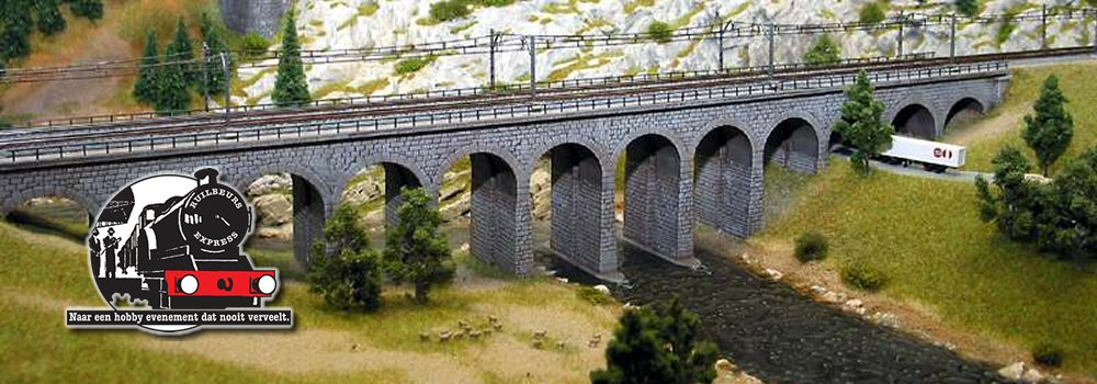 Foto van een deel van een modelbaan met een brug in een berglandschap en het logo van de modelspoorbeurs